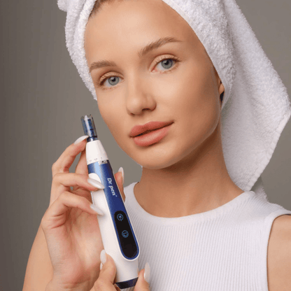 Mujer con toalla alrededor del cabello sosteniendo una pluma Dr. Pen A11 microneedling - dispositivo profesional de cuidado de la piel para una piel más lisa y firme.