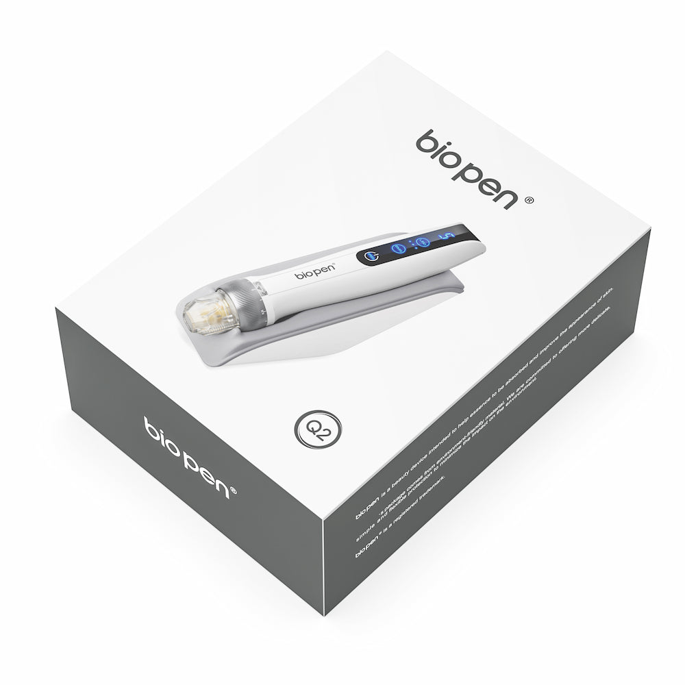 Bolígrafo Q2 microneedling mostrado en la parte superior de una caja de producto blanca y gris con logotipo claro e imagen del bolígrafo en la tapa.