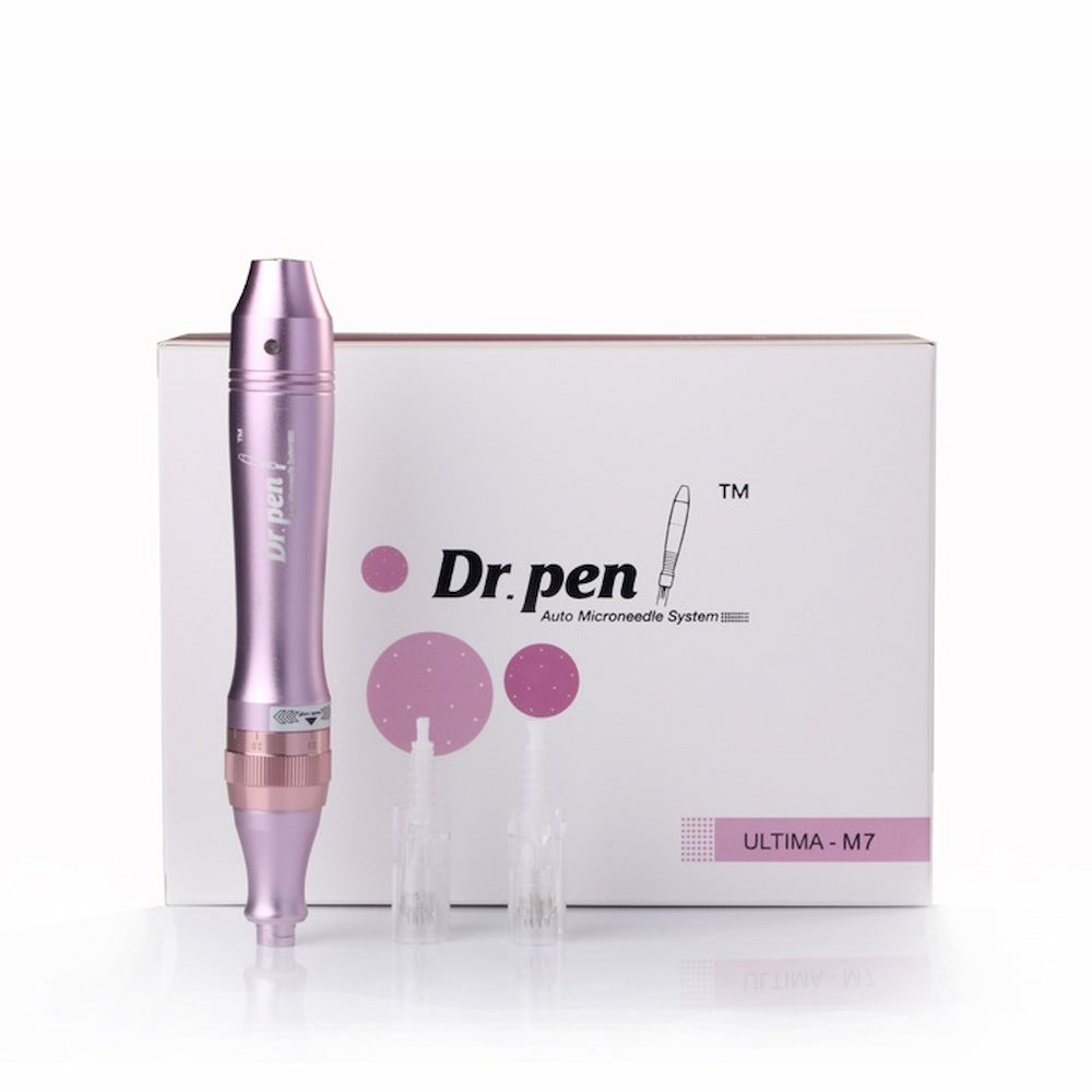 Pluma rosa Dr. Pen Ultima M7 microneedling frente a un empaque de producto blanco, junto con dos cabezales de aguja transparentes.