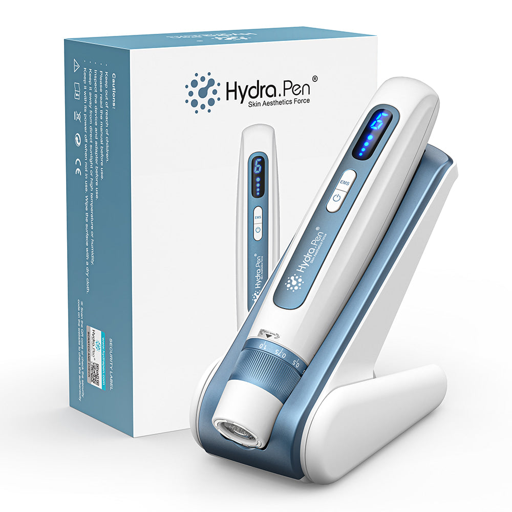 HydraPen H5 pluma microneedling en diseño blanco y azul colocada en su base de carga junto al embalaje original, para cuidado profesional de la piel e infusión de suero.